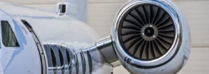 Close-up of a polished private jet showing its jet engine and glossy fuselage.
